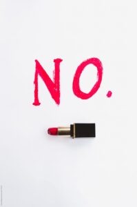 Photo of the word NO in red lettering against a white background with a red lipstick underneath